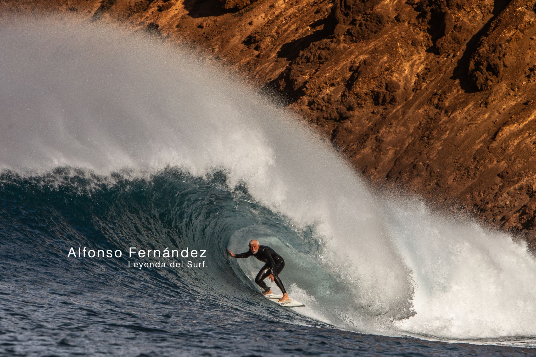 Surfer riding a wave near cliffs.