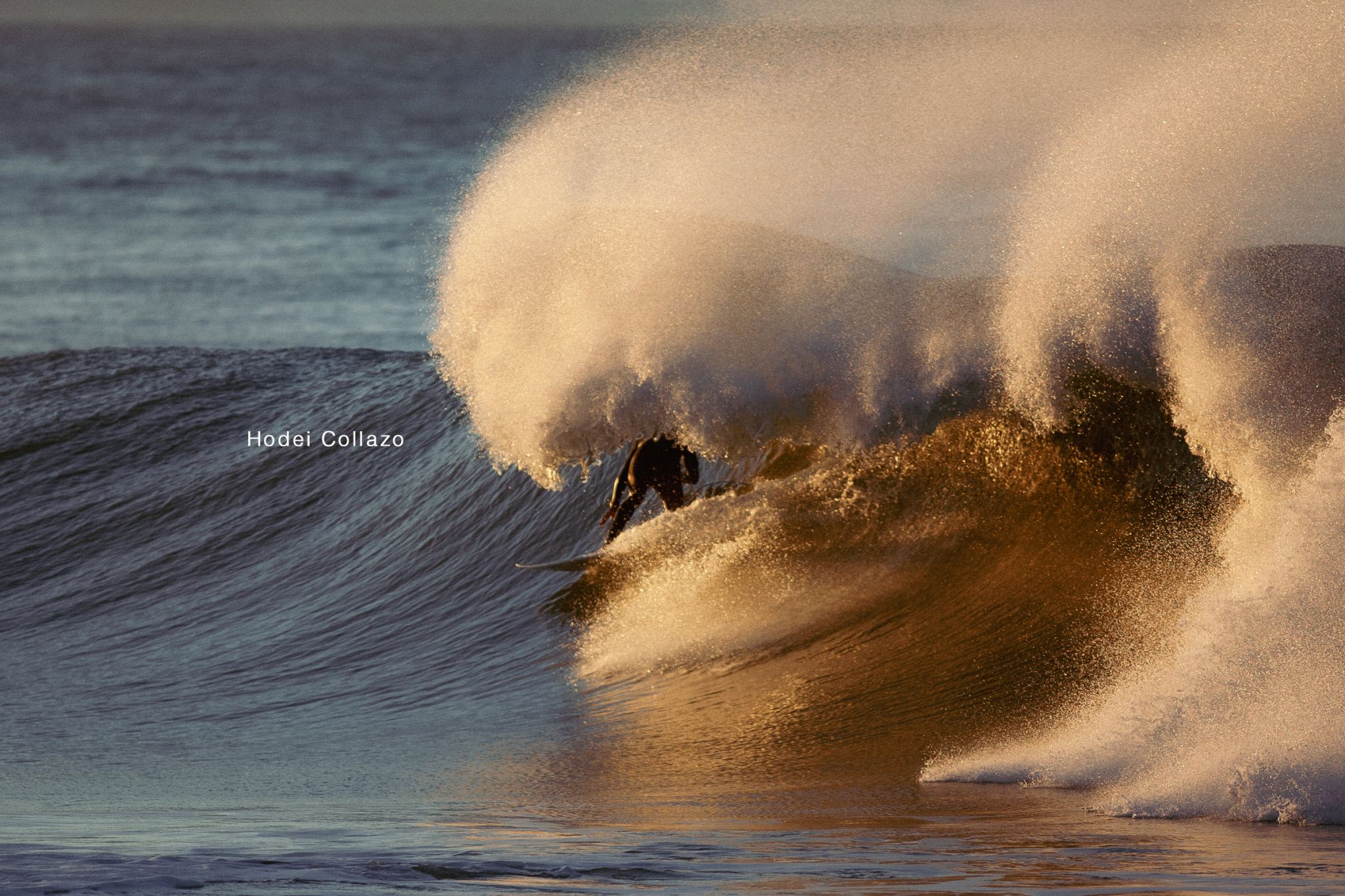 Surfer riding a wave at sunset near Farmhouse7.