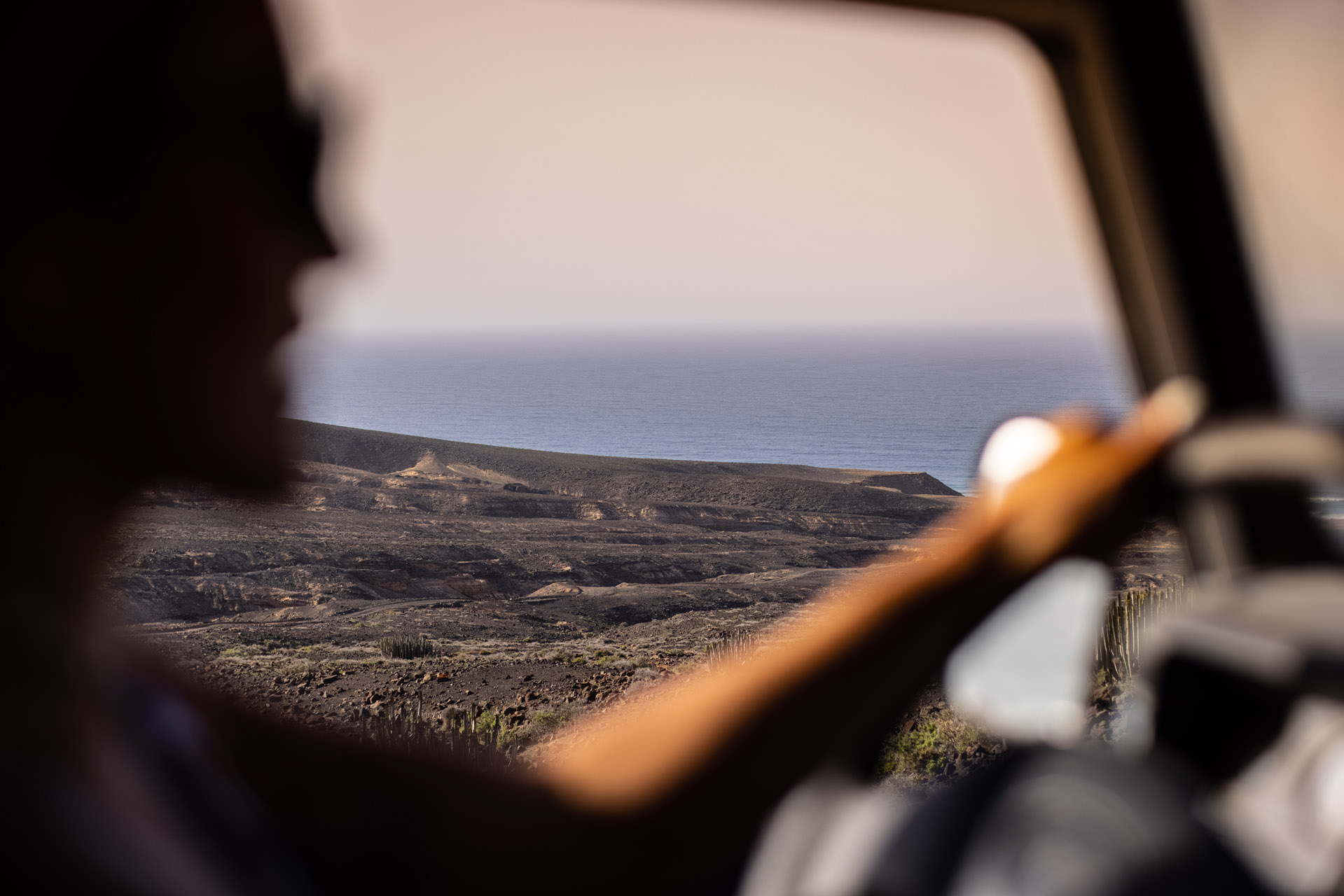 Fahrerin in einem Geländewagen mit Ausblick auf das Meer.