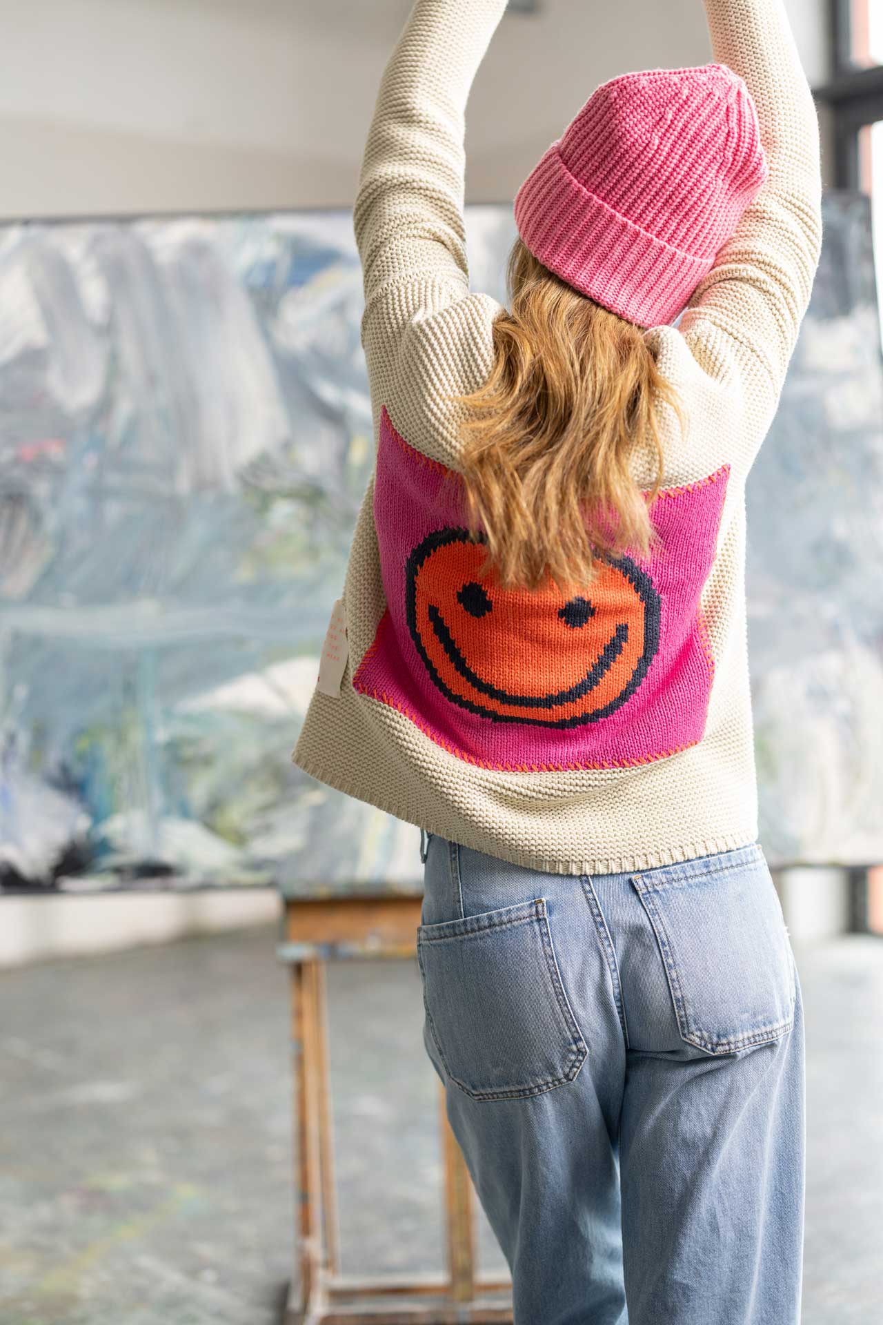 Frau mit Smiley-Pullover in Atelier.