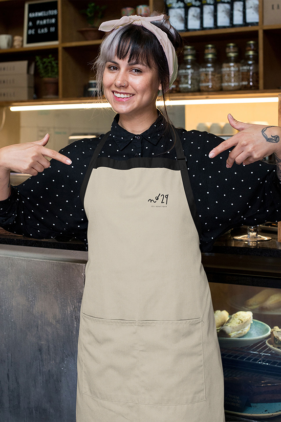 Eine fröhliche Frau im Schürze zeigt auf sich selbst.