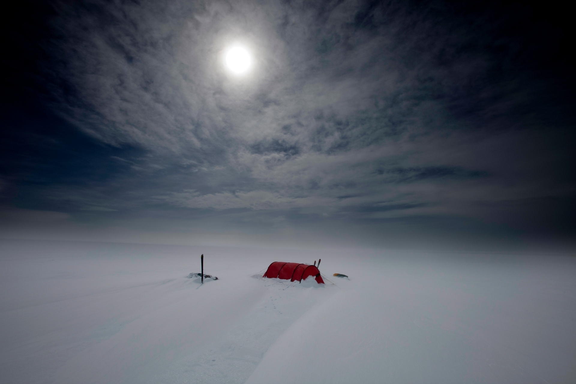 Rotes Zelt in einer verschneiten Landschaft bei Tag.