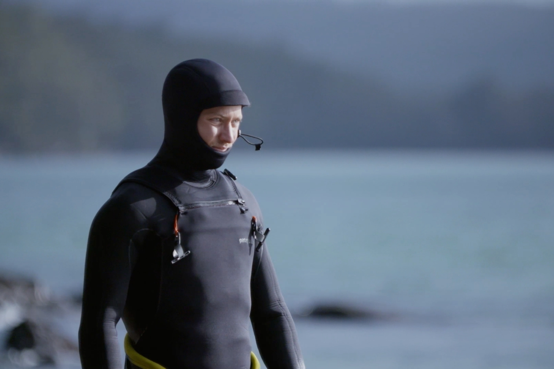 Ein Surfer in einem schwarzen Neoprenanzug am Strand.