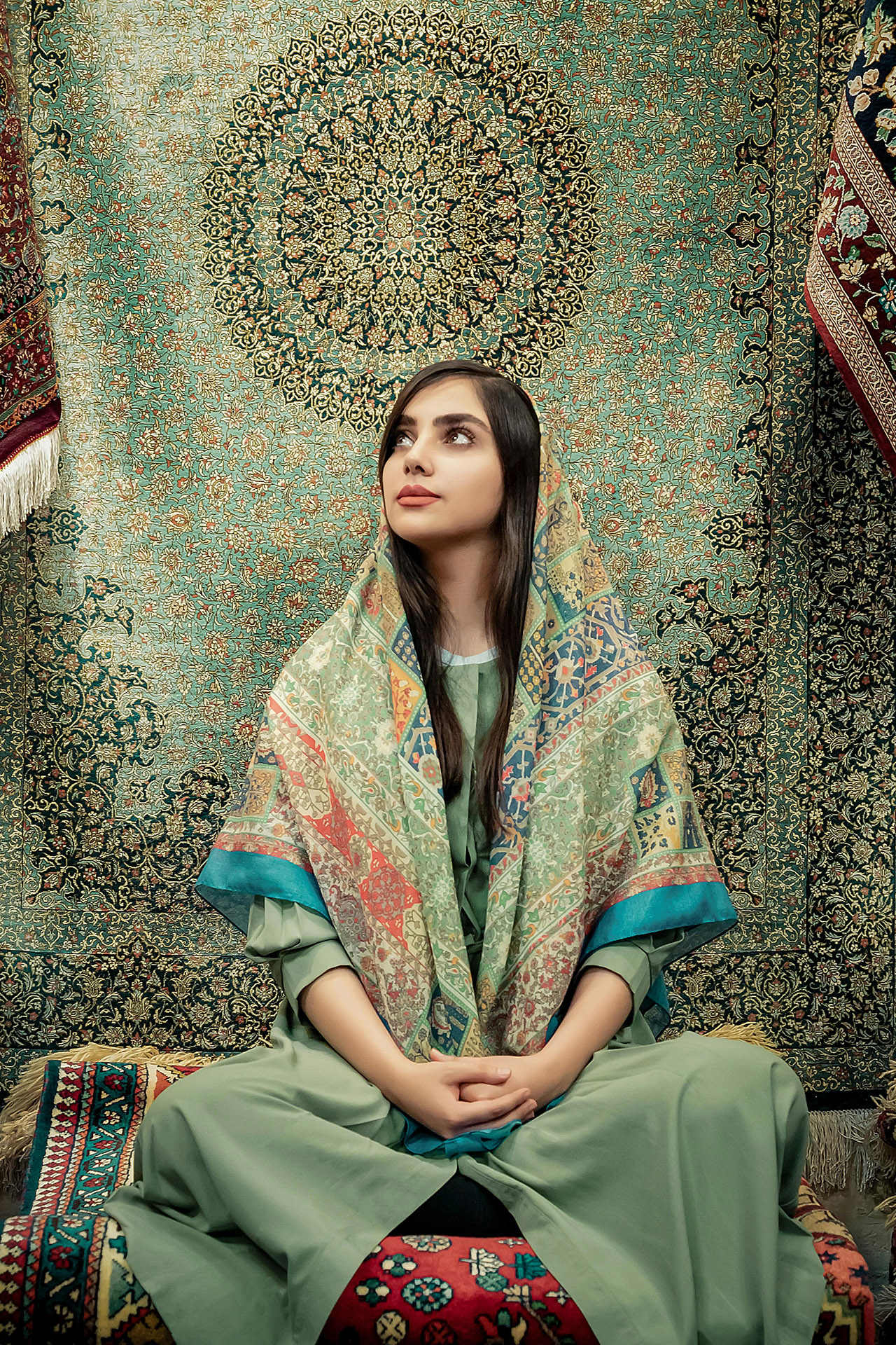 Frau mit Kopftuch vor Teppichen