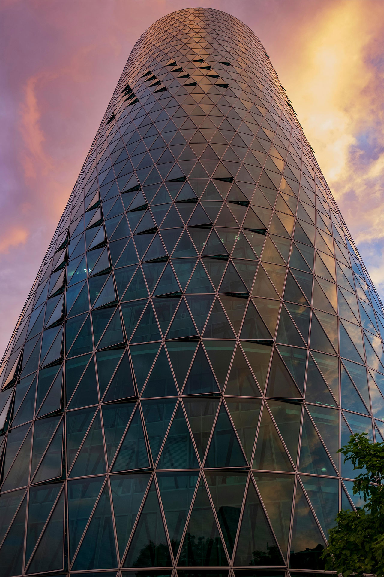 Modern gläserner Wolkenkratzer unter einem bunten Himmel.