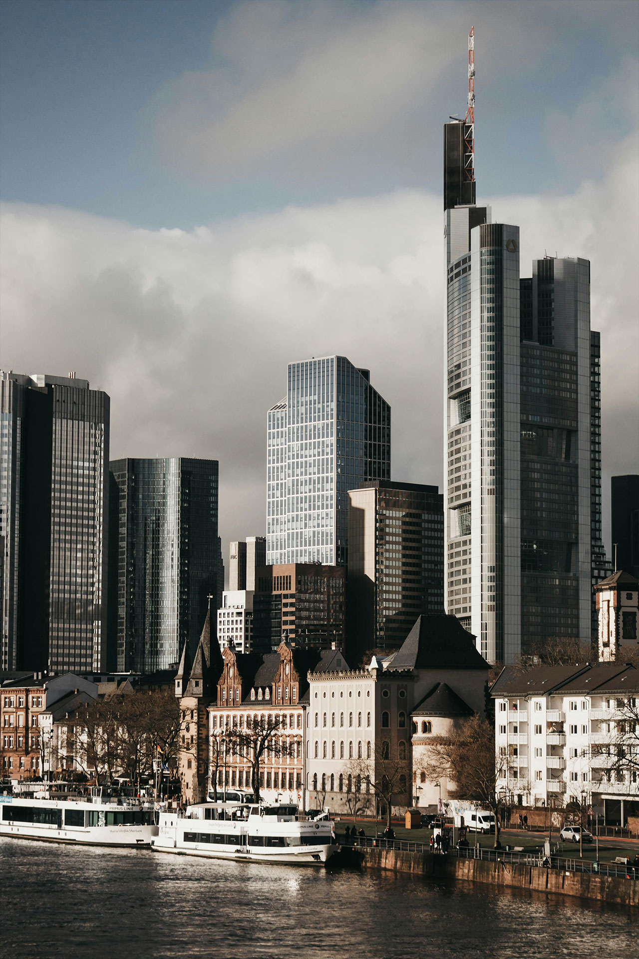 Stadtansicht mit modernen Hochhäusern und Altbauten am Fluss.