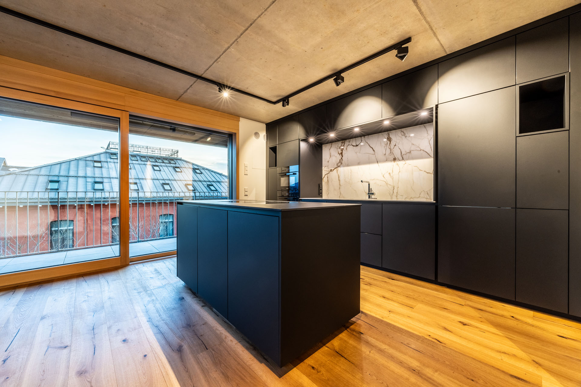 Moderne Küche mit schwarzen Möbeln und Holzboden.