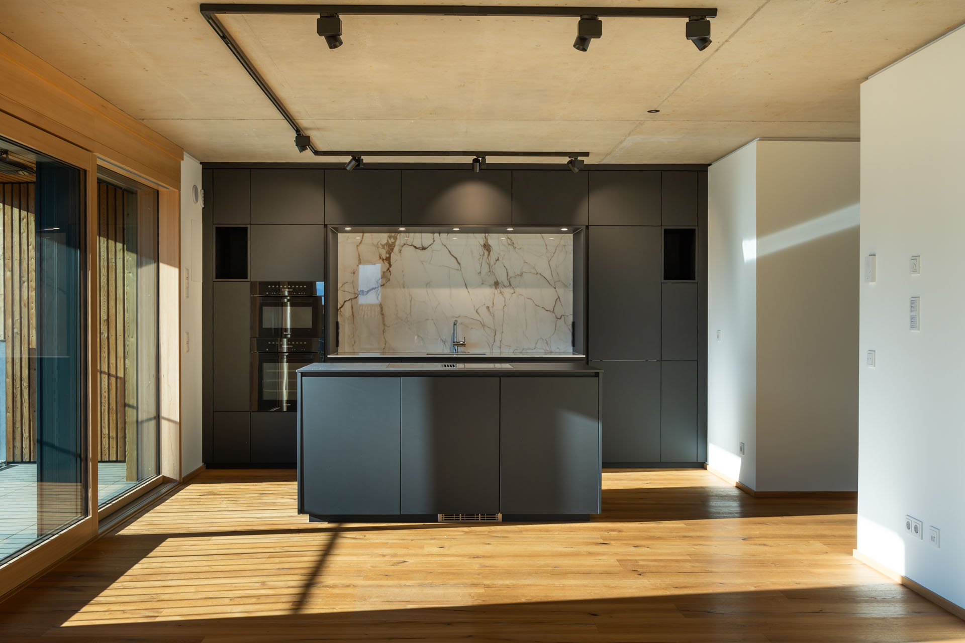 Moderne Küche mit Holzfußboden und Marmorrückwand.