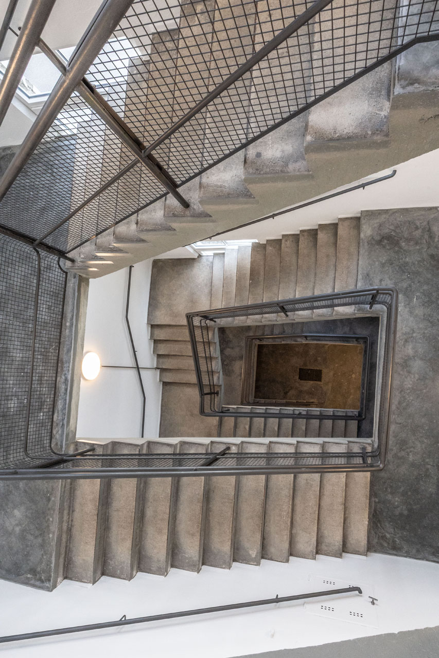 Blick auf eine helle Treppe mit Geländer von oben